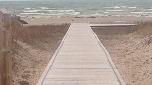 A wooden boardwalk leading to a beach with waves in the background. - Sandy Trail Lodge 3 Bedroom Cottage Backs on to Sauble Beach  (Sauble Beach)