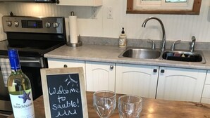 A kitchen counter with a bottle of wine, a welcome sign, and two glasses. - Sandy Trail Lodge 3 Bedroom Cottage Backs on to Sauble Beach  (Sauble Beach)