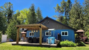 A blue house with a covered patio, a barbecue area, and a small shed. - Sandy Trail Lodge 3 Bedroom Cottage Backs on to Sauble Beach  (Sauble Beach)