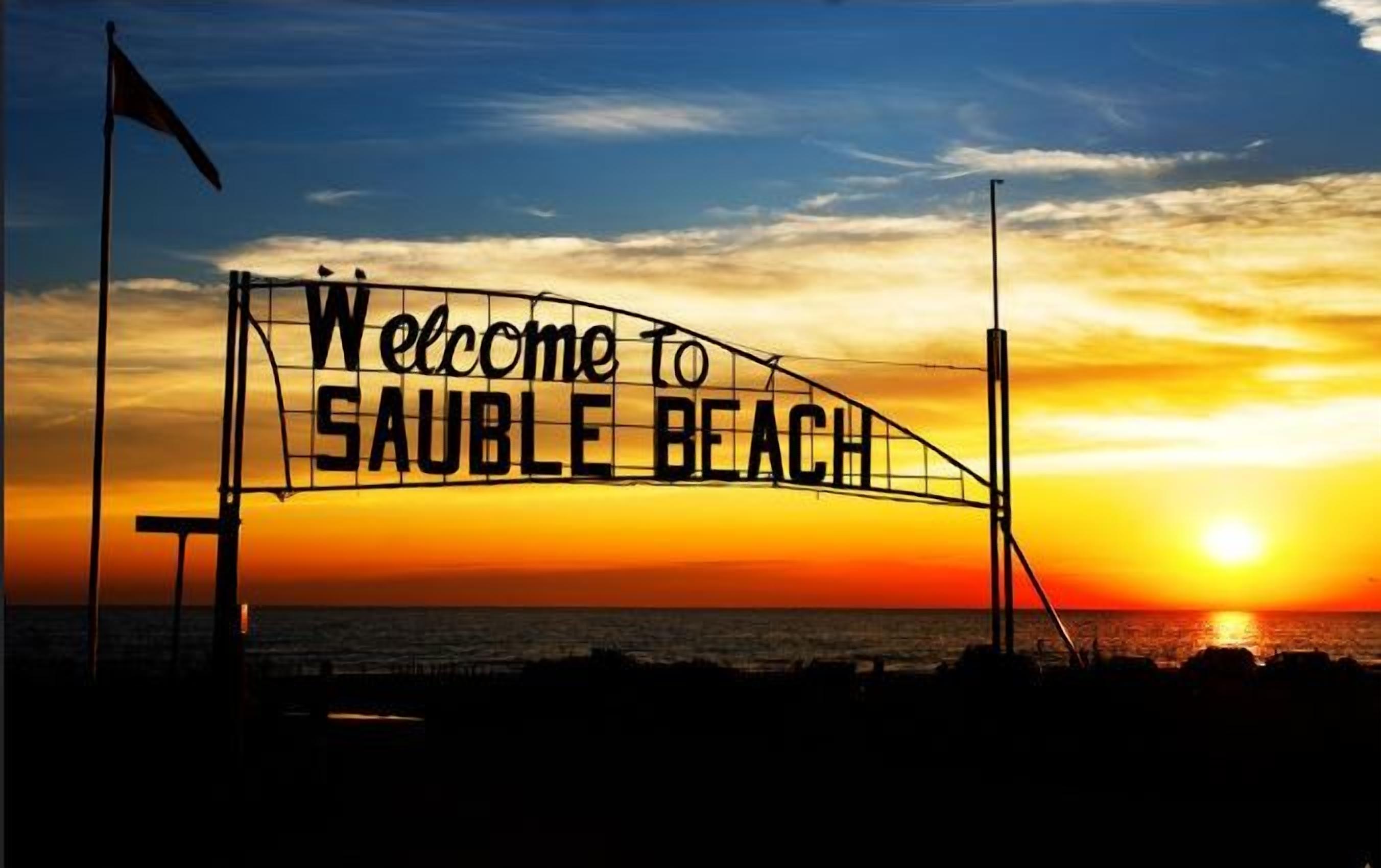 Ein Sonnenuntergang mit einem Schild, auf dem 'Welcome to SAUBLE BEACH' steht.