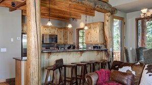 Une cuisine rustique avec des meubles en bois, un four à micro-ondes encastré et un coin bar avec des tabourets.