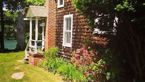A brick house with a chimney, a small porch, and a garden with stepping stones. - Waterfront! Charming 4BR Cottage on the Niantic River!  (Waterford)