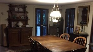 A dining room with a wooden table and chairs, a chandelier, a clock, and a rug. - Waterfront! Charming 4BR Cottage on the Niantic River!  (Waterford)