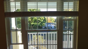 Una ventana con vista a una casa y un árbol, y la palabra 
