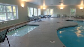 Una piscina interior con varias pistas, sillas de descanso y mesas.