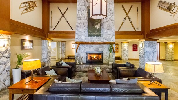 A lobby with a stone fireplace, leather sofas, and a wooden coffee table. - SKI IN/OUT, close to gondola and village - 1 bd, Hot Tubs/pool (Whistler)