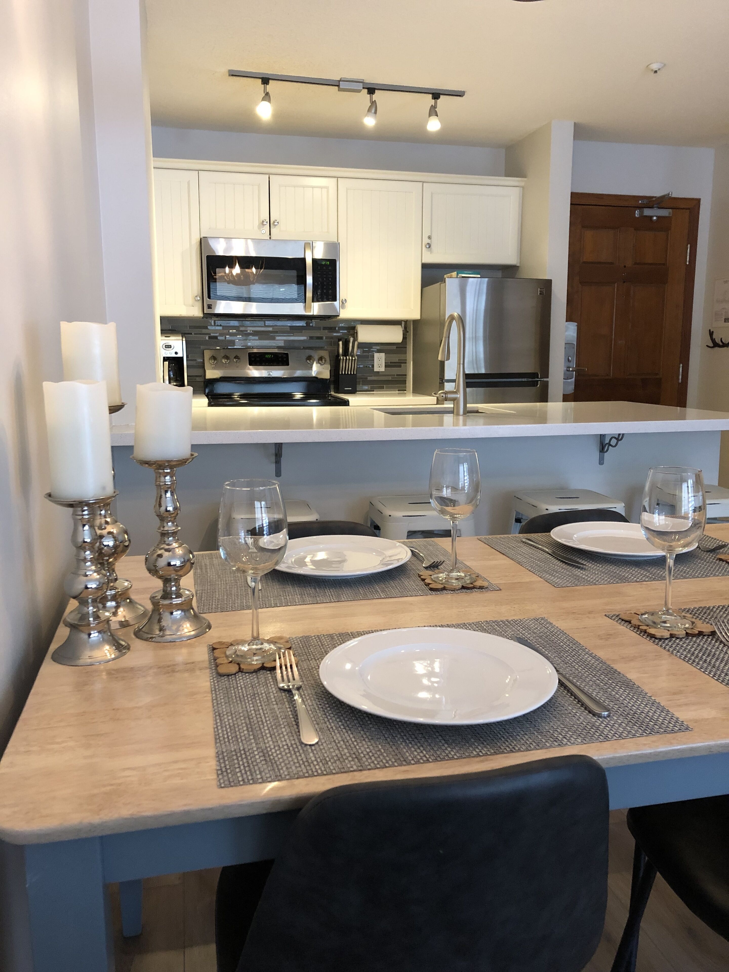 Een eetruimte met een tafel voor vier personen, compleet met borden, glazen en kaarsen.