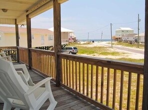 Relax on the deck overlooking the sandy beach with comfortable seating for a serene escape.