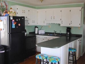 Enjoy casual dining at this kitchen with a sink, coffee maker, and small island with stools.