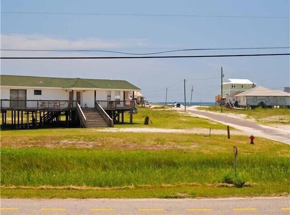 A beachfront building with a balcony and a staircase leading to a pier.