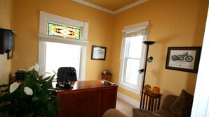 A room with a wooden desk, a wicker plant, a brown sofa, and a framed motorcycle picture on the wall. - AWESOME STURGIS HOME FOR STURGIS RALLY (Sturgis)