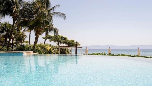 A clear blue infinity pool with a view of the sea and palm trees. - Best Amazing Deal  Beach Front & Stunning Views +Chef & Maid included (Punta de Mita)