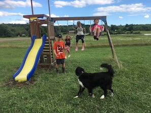 Children can play on the playground's swing set and slide in this open grassy area.