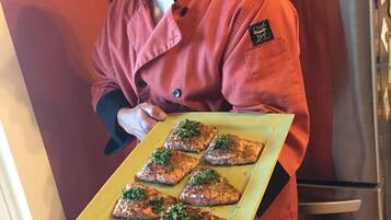 Una persona con delantal de chef rojo sostiene una bandeja con varios platos.