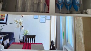 Un comedor con una mesa lista para dos, un sofá y una ventana con luz natural.