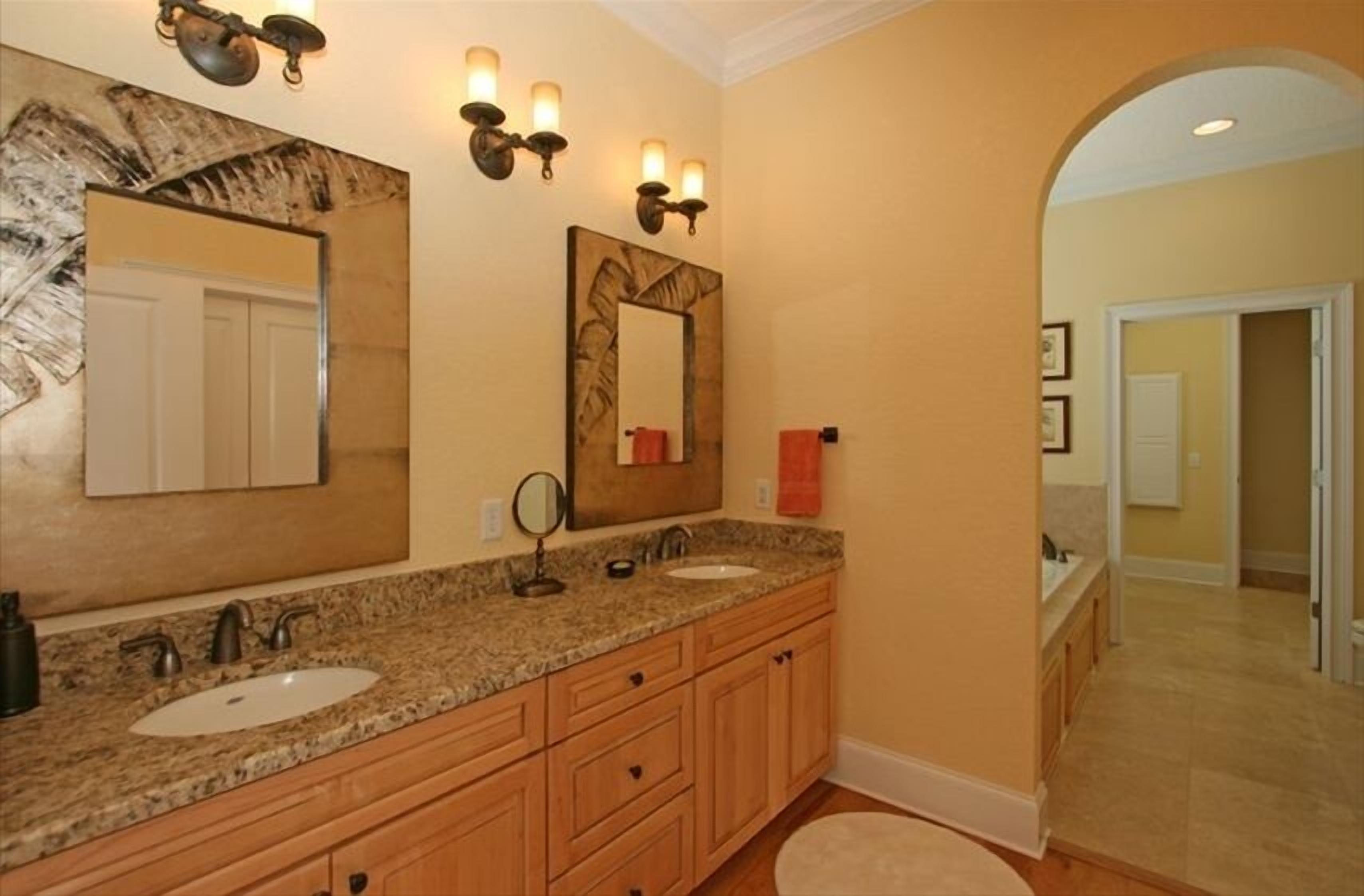 A bathroom with two sinks, wooden cabinets, and a mirror with wall sconces.