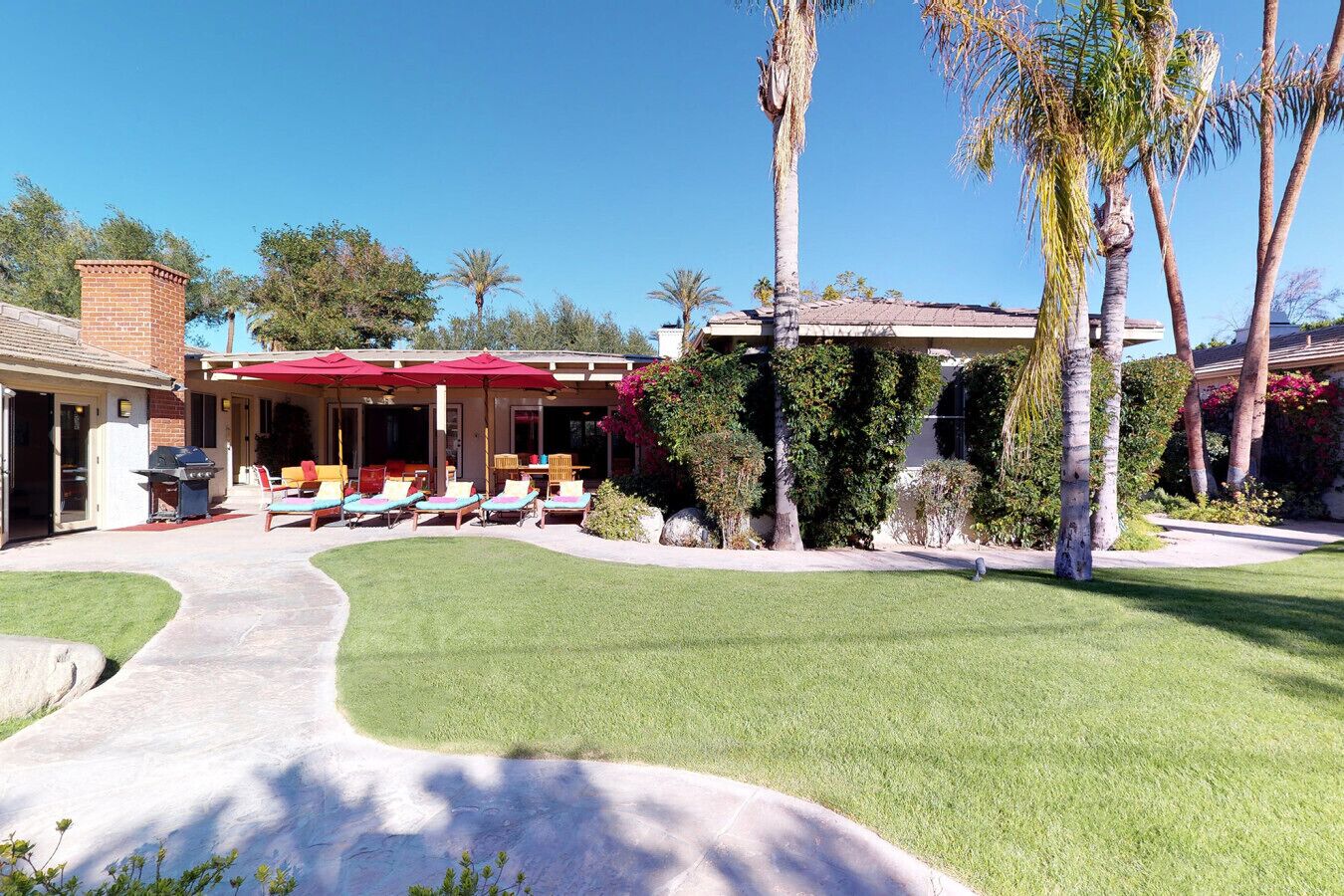 Una casa con un patio, mobiliario exterior y un césped cuidado.