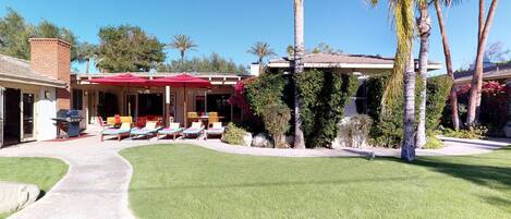 A house with a patio area, outdoor furniture, and a well-maintained lawn.