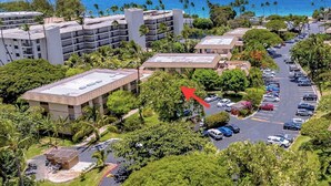 Une vue aérienne d’un hôtel situé sur la côte, composé de plusieurs bâtiments, de parkings et offrant une vue dégagée sur l’océan.