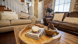 A cozy living room with a wooden coffee table, a brown leather sofa, and a beige couch. - Stylish Escape in Historic Warehouse District (New Orleans)