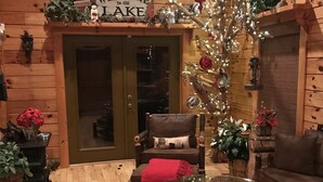 A cozy cabin interior with a wooden floor, a glass coffee table, a leather armchair, and a Christmas tree. - Double-Decker Dock - Beautiful View (Blairsville)