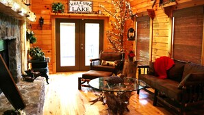 A cozy cabin interior with a stone fireplace, a glass coffee table, a leather sofa, and a sign reading "Welcome to the Lake". - Double-Decker Dock - Beautiful View (Blairsville)