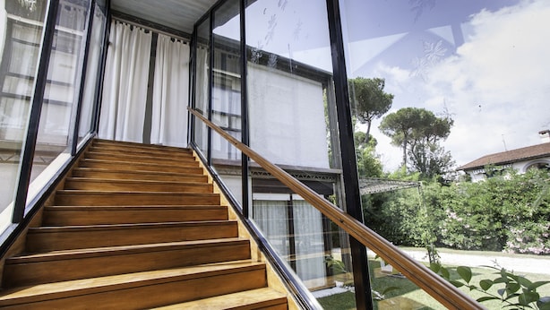 A wooden staircase with glass railings leading to a modern building with large windows. - Architectural/Minimal Villa in Forte dei Marmi, Roma Imperiale (Forte dei Marmi)