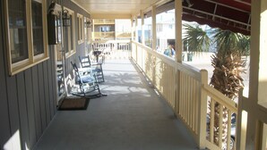 A covered porch with a railing, a bench, and a door leading to a balcony. - Beautiful Efficiency Condo Across The Street from Beach. Great Pool & Deck Area. (North Myrtle Beach)