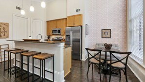 Una cocina moderna con armarios de madera, electrodomésticos de acero inoxidable y una isla central con taburetes de bar.