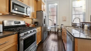Una cocina moderna con electrodomésticos de acero inoxidable, armarios de madera y un amplio ventanal que ofrece luz natural.