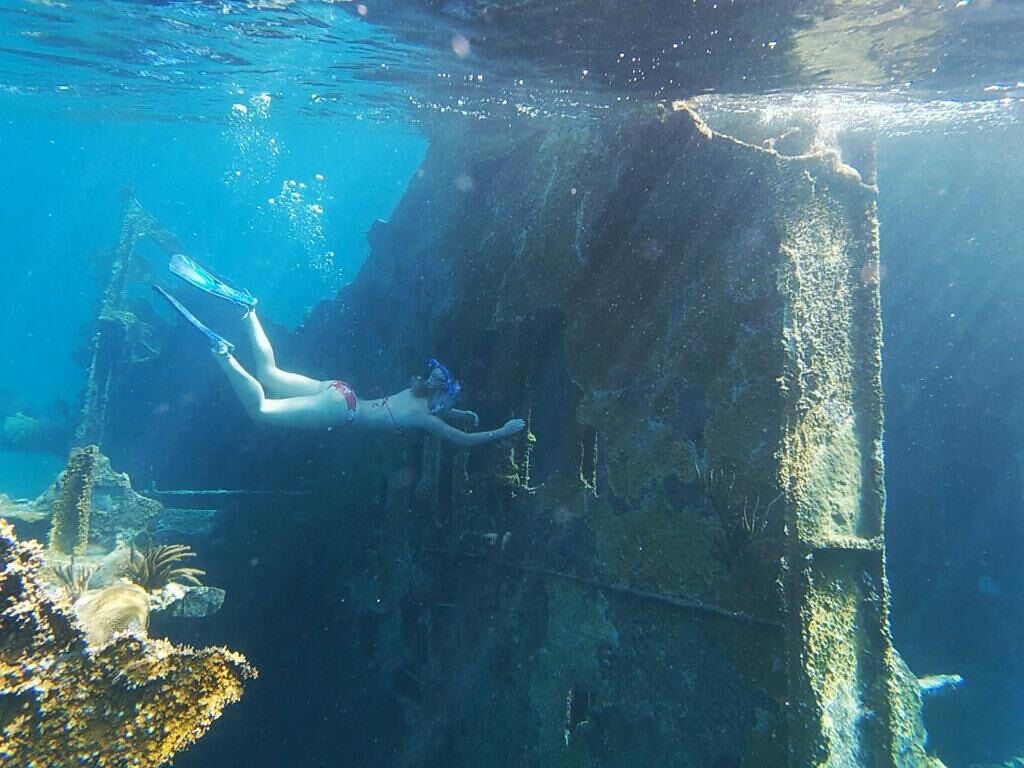 A person snorkeling near a large underwater structure.