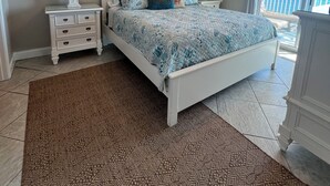 A bedroom with a bed, nightstands, a ceiling fan, a framed picture, and a view of the ocean. - Crystal Shores, Gulf Shores. Family Friendly Beachfront Condo w/ Pool,GYM & more (Gulf Shores)
