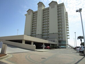 Et hotel med flere etager, en central indgang og en parkeringsplads foran.