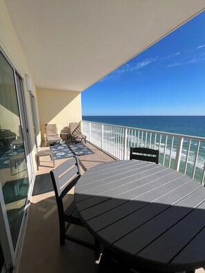En balkon med et bord og stole, med udsigt over havet.