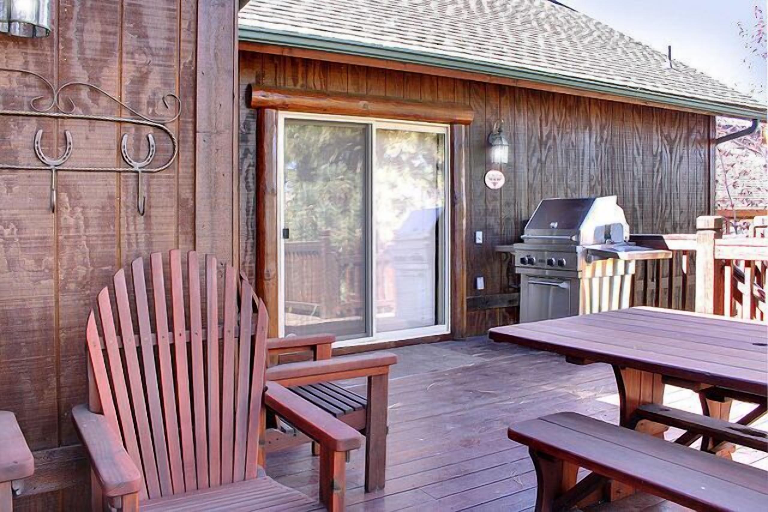 Una terraza de madera con una parrilla, un puerta corrediza de vidrio y una silla de madera.