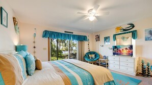 A bedroom with a bed, a chair, a dresser, and a ceiling fan. - Serenity by the Sea at Whitman Point. Gulf front and Screened Porches (Cedar Key)