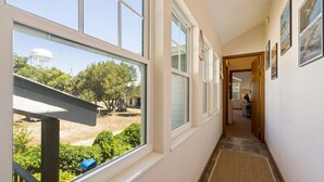 A hallway with large windows, a view of a water tower, and a door leading to a room. - Serenity by the Sea at Whitman Point. Gulf front and Screened Porches (Cedar Key)