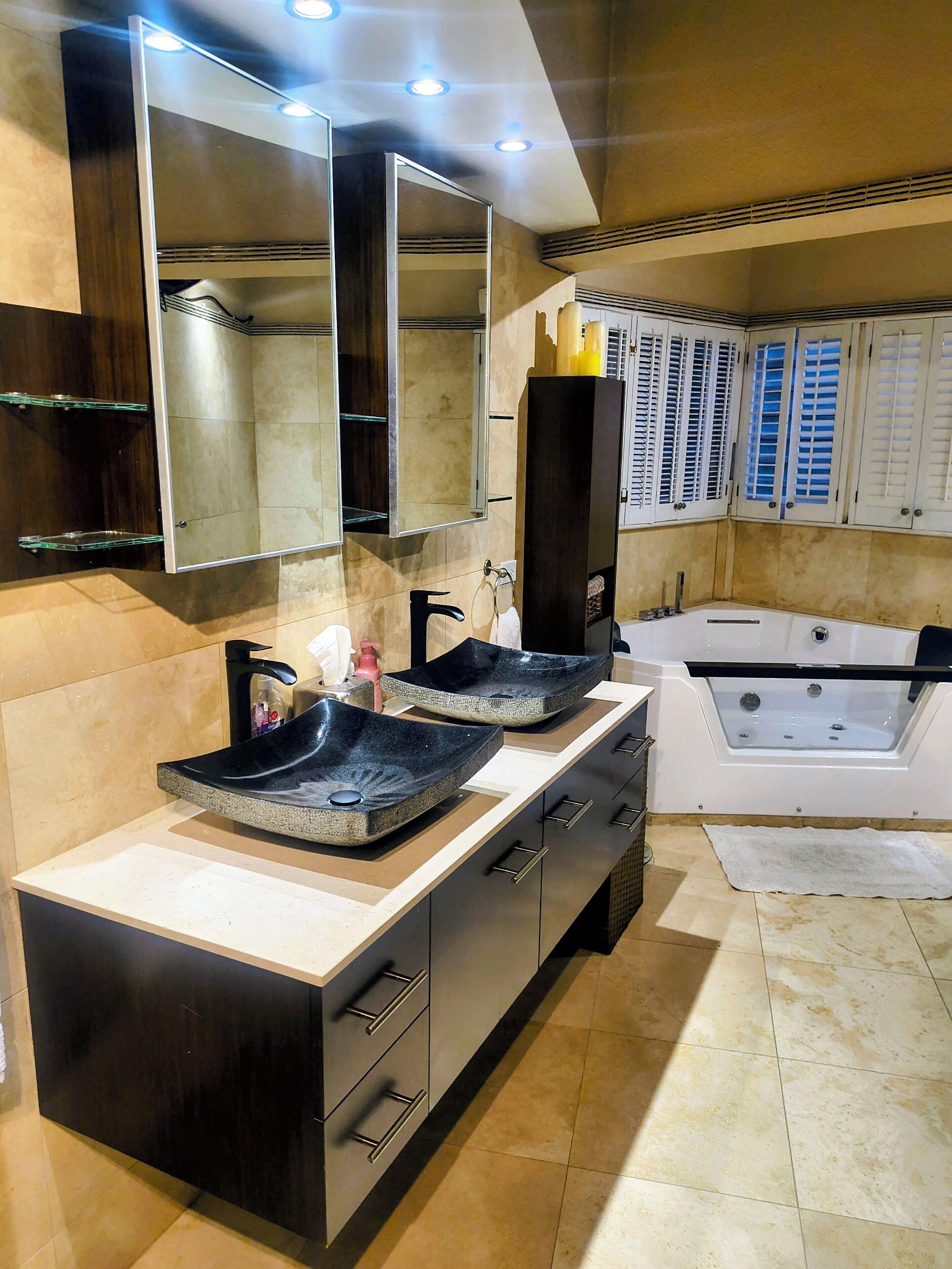 A modern bathroom with a double sink, a large mirror, a bathtub, and a vanity with drawers.