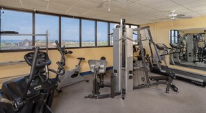 Un gimnasio con máquinas de cardio, equipo de levantamiento de pesas y un espejo grande.