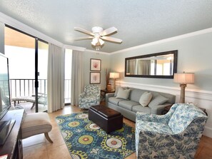 A hotel room with a balcony, a sofa, a chair, a coffee table, a TV, and a ceiling fan. - Beachfront 2BR/2BA | Direct Gulf Front | Resort Amenities | Sleeps 8 (Orange Beach)
