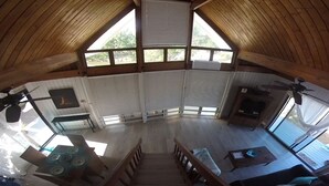 A spacious loft-style room with a high ceiling, large windows, a fireplace, and a dining area.