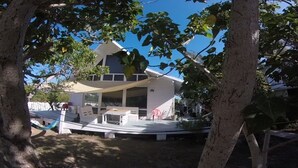 A two-story house with a covered patio area, a hammock, and a pink chair.
