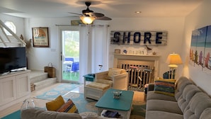 A cozy living room with a television, sofa, and a fireplace. There is a sign that reads "SHORE" and a beach-themed painting on the wall. - GREAT LOCATION!  Million dollar view of the Salt Pond  (Bethany Beach)