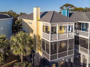 Stunning multi-story building with a unique design, offering a glass-enclosed upper floor and beautifully maintained garden with palm trees.