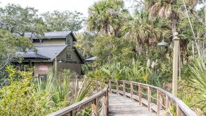 A wooden boardwalk leading to a building with a sign reading "The Creek House." - The Misty Breeze! Cabana Club, Ocean View, Golf Cart  (Fripp Island)