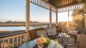 A covered outdoor seating area with a glass table, chairs, and a bowl of snacks. - The Misty Breeze! Cabana Club, Ocean View, Golf Cart  (Fripp Island)