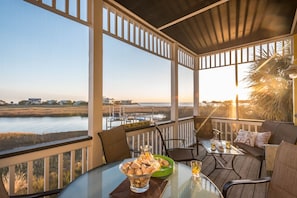 Relax in a serene outdoor space with a clear view of the water and distant shoreline, featuring a comfortable seating area with a glass table and cushioned seating.
