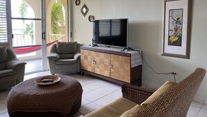 Una sala de estar con televisión, sofá, sillón y aparador.