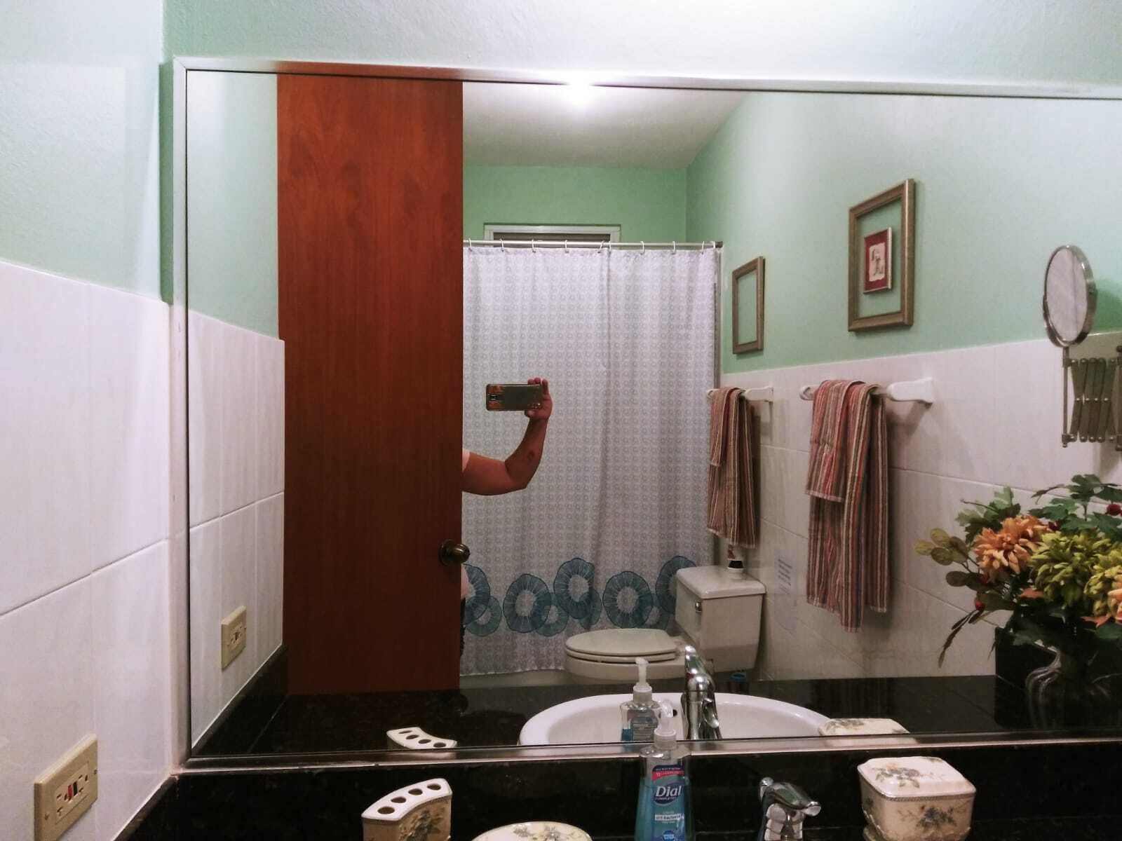 Baño con espejo, lavamanos, inodoro y cortina de ducha.