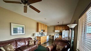 A living room with a brown leather sofa, a dining table, and a kitchen area with wooden cabinets and appliances. - Looking for an Alternative to a Big Box Motel?  We're it! (Gardiner)